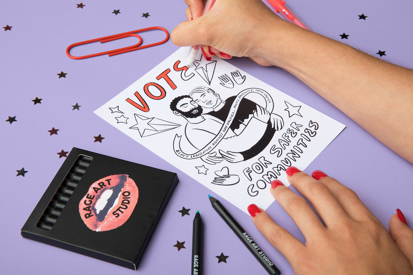 Image of a woman coloring in the "Vote for Safer Communities" card. Also pictured is the pack of 12 colored pencils that come with each kit.